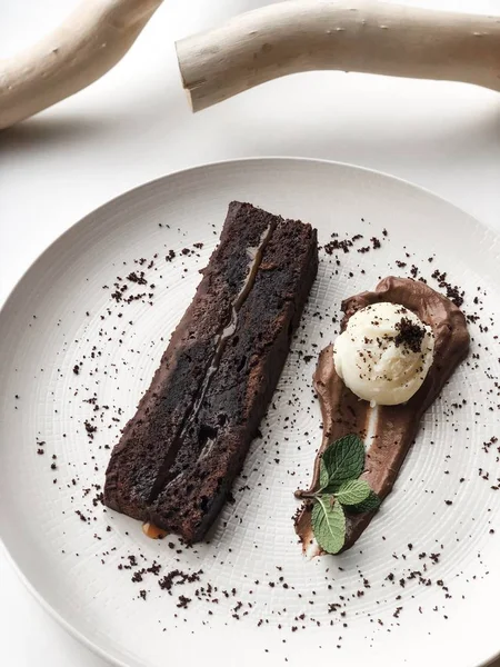 Beyaz plaka üzerinde ahşap dallar yanında çikolata tatlı kek