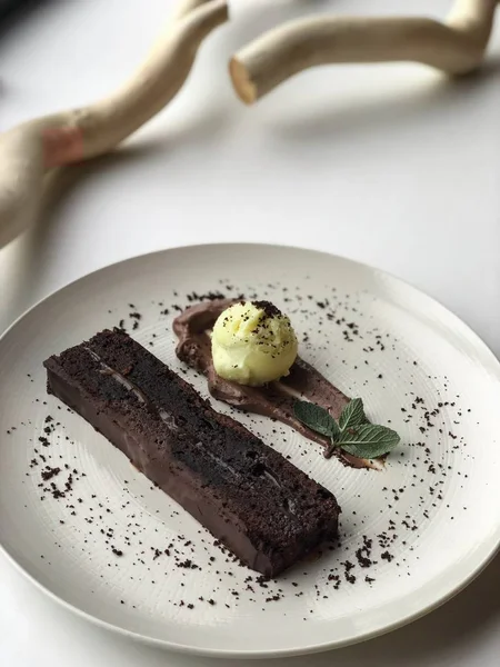 Beyaz plaka üzerinde ahşap dallar yanında çikolata tatlı kek