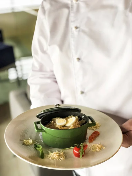 Aşçı bir tabak makarna Fettuccine bir metal çanak tavşan ve yumurta ile tutan (parmesan, domates)