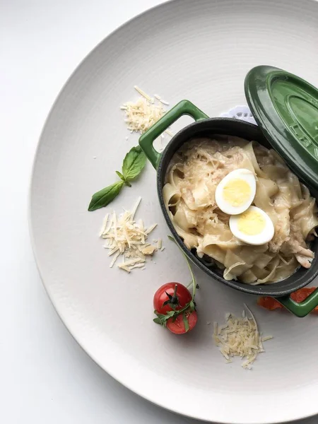 bir servis restoran masasında bir metal çanak tavşan ve yumurta ile fettuccine makarna (parmesan, domates)