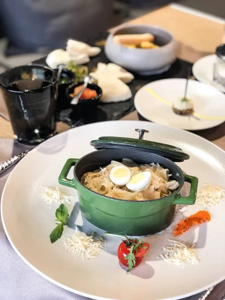 bir servis restoran masasında bir metal çanak tavşan ve yumurta ile fettuccine makarna (parmesan, domates)