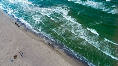 Yürüyen insanlarla sahilin üzerinde uçan drone