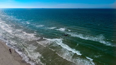 Yürüyen insanlarla sahilin üzerinde uçan drone