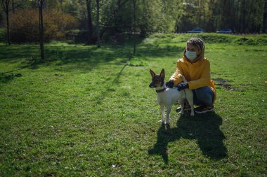 Maskeli bir kız köpekle yürüyor.