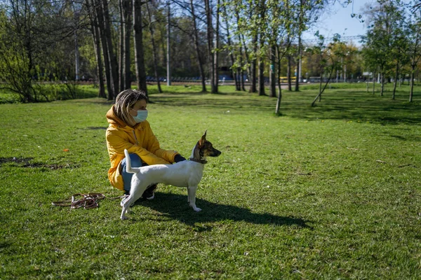 Девушка в маске гуляет с собакой — стоковое фото