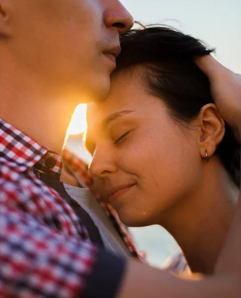 Nahaufnahme Porträt eines schönen jungen Paares, das lächelt, bevor es sich gegen Sonnenuntergang küsst — Stockfoto