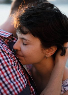 Gün batımına karşı öpüşmeden önce gülümseyen genç bir çiftin yakın portresi.