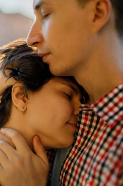 Gün batımına karşı öpüşmeden önce gülümseyen genç bir çiftin yakın portresi.