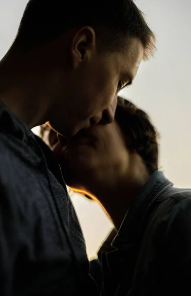 Gün batımına karşı öpüşmeden önce gülümseyen genç bir çiftin yakın portresi.