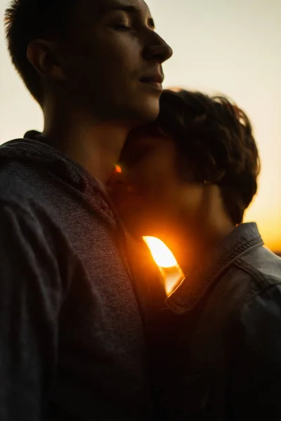 Gün batımına karşı öpüşmeden önce gülümseyen genç bir çiftin yakın portresi. — Stok fotoğraf
