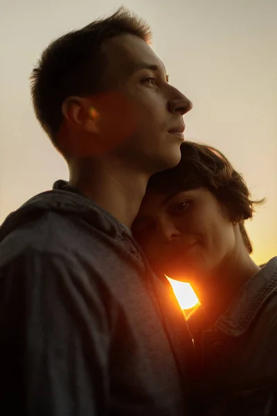 Gün batımına karşı öpüşmeden önce gülümseyen genç bir çiftin yakın portresi.