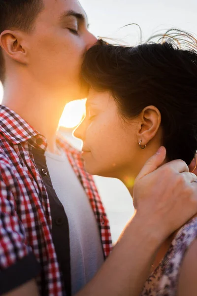 Nahaufnahme Porträt eines schönen jungen Paares, das lächelt, bevor es sich gegen Sonnenuntergang küsst — Stockfoto