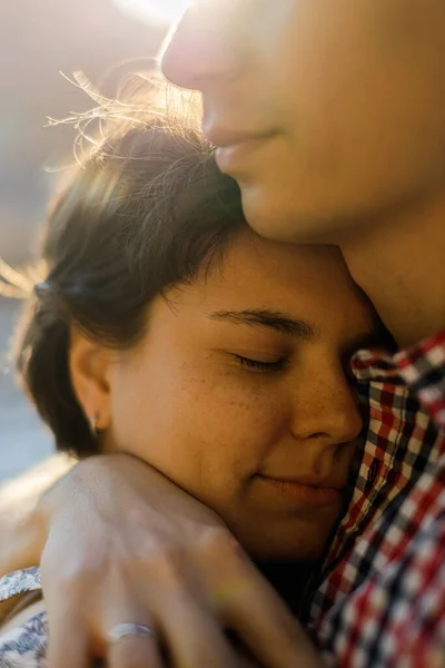 Gün batımına karşı öpüşmeden önce gülümseyen genç bir çiftin yakın portresi.