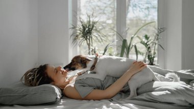 Kızlar küçük bir köpekle yataktalar.