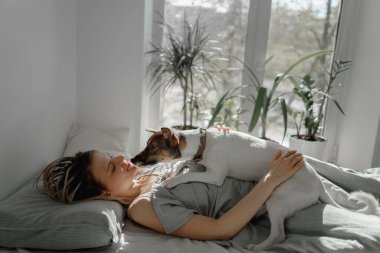 Kızlar küçük bir köpekle yataktalar.