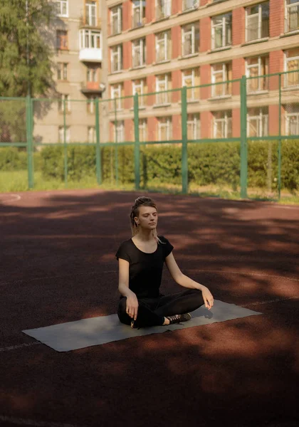 Fiatal fitneszlány nyújtózkodik és jógázik egy játszótéren — Stock Fotó