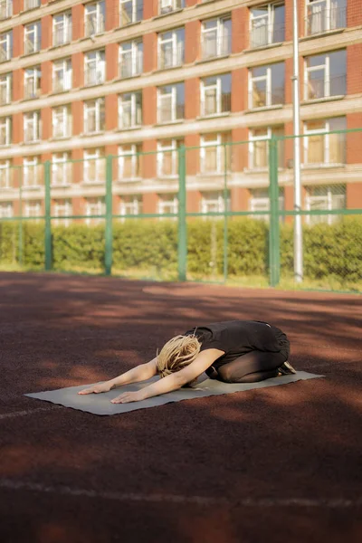 Fiatal fitneszlány nyújtózkodik és jógázik egy játszótéren — Stock Fotó