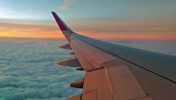 下の雲と夕焼け空に飛行機の翼 — ストック写真