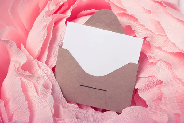 Craft postal envelope with attached paper on a pink background. Space for text or design.