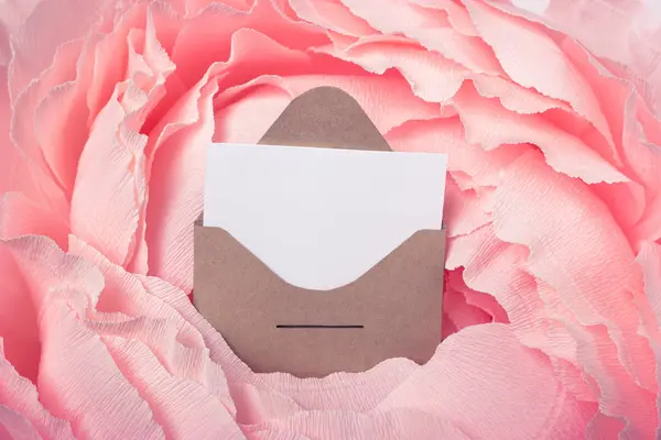 Craft postal envelope with attached paper on a pink background. Space for text or design.