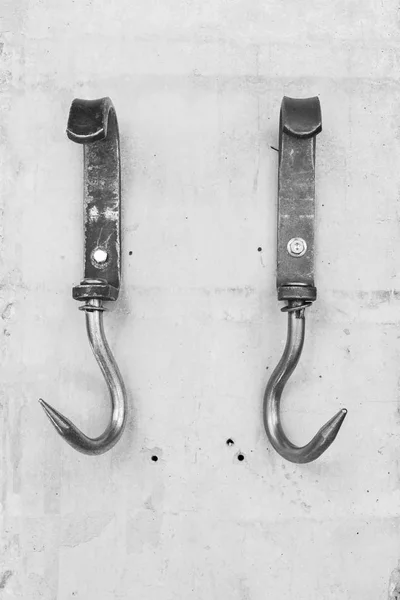 Vintage metal hooks for hay or meat attached to a concrete wall