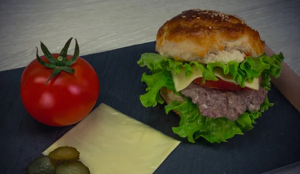 Cheeseburger fatto in casa con una fetta di formaggio e pomodoro su un dar — Foto Stock