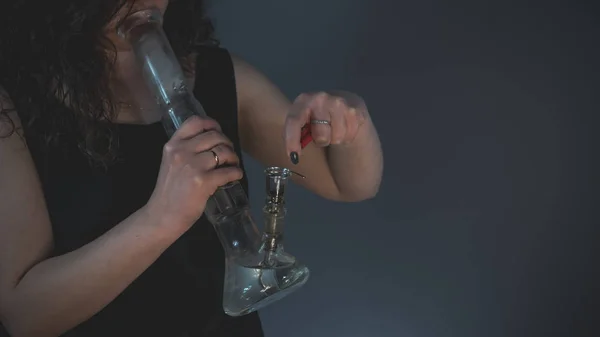 The person smoking marijuana with bong, close-up.