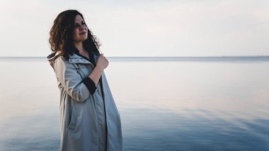 Deniz kenarında duran dalgın kadın. 