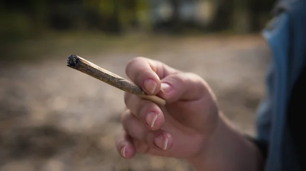 De persoon die marihuana gewricht buitenshuis roken. — Stockfoto