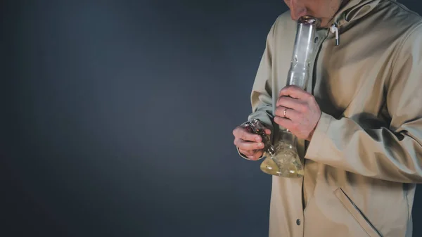 Молодой человек курит медицинскую марихуану с бонгом . — стоковое фото