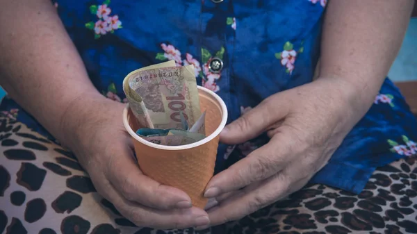 Stara kobieta nasuwa na jałmużny. Zbliżenie pieniędzy i monet w ręku p — Zdjęcie stockowe