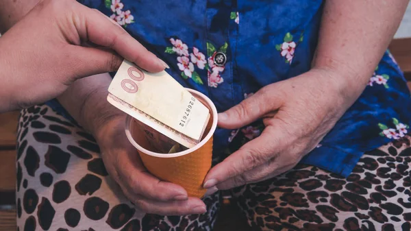 Oude vrouw smeekt voor aalmoes. Close-up van geld en munten in de hand van p — Stockfoto