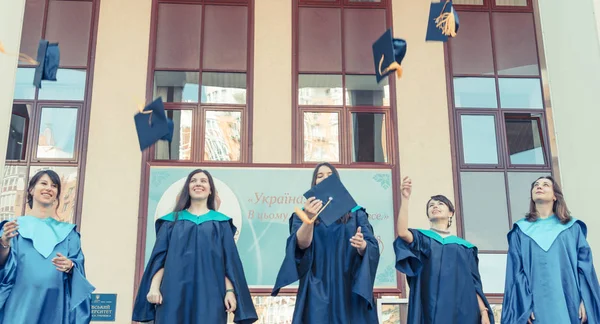 Absolwenci Uniwersytetu rzucanie kapelusze ukończenia w powietrzu. Grupa — Zdjęcie stockowe