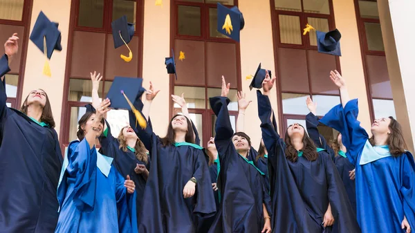 Universitaire afgestudeerden gooien afstuderen hoeden in de lucht. Groep — Stockfoto