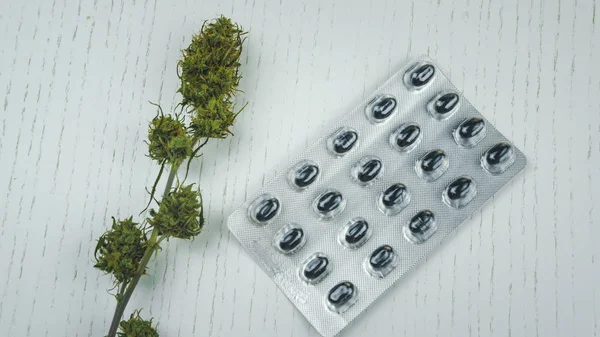 Marijuana buds and pills lie on the white table. — Stock Photo, Image