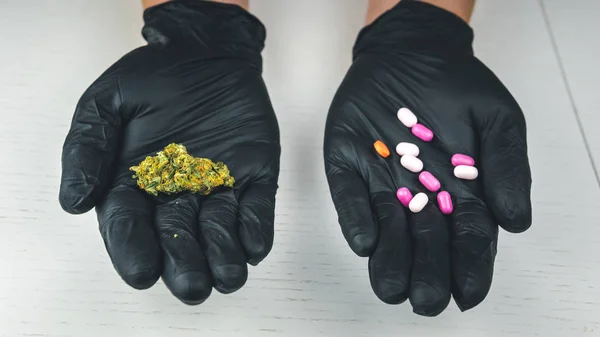 The person holds in his hand medical marijuana buds and pills. — Stock Photo, Image