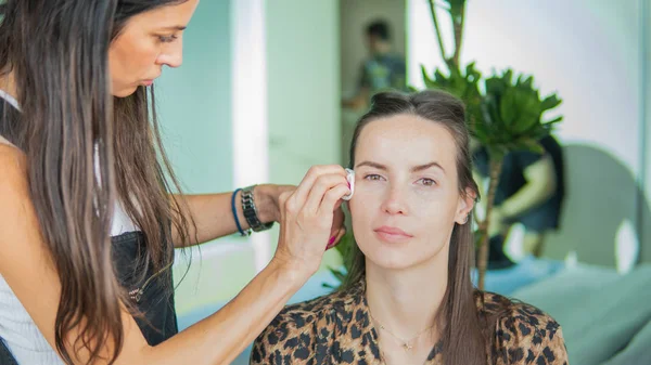 Artista de maquillaje haciendo maquillaje profesional para mujer joven. Mujer a — Foto de Stock