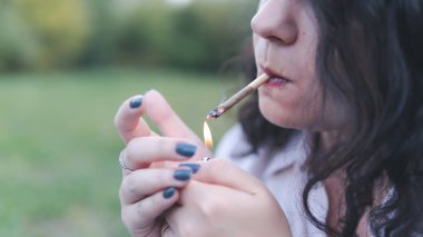 Kız açık havada tıbbi marihuana içerken, yakın çekim. Cannabi