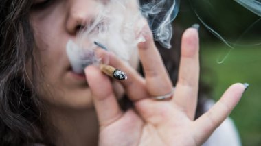 Kız açık havada tıbbi marihuana içerken, yakın çekim. Cannabi