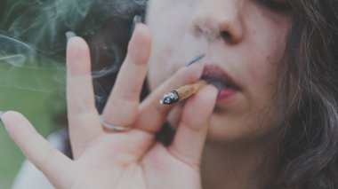 Kız açık havada tıbbi marihuana içerken, yakın çekim. Cannabi