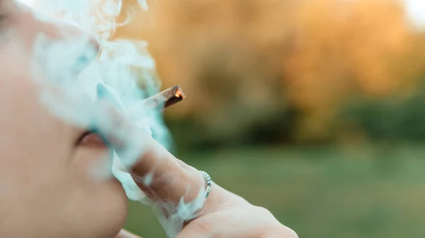 Kız açık havada tıbbi marihuana içerken, yakın çekim. Cannabi