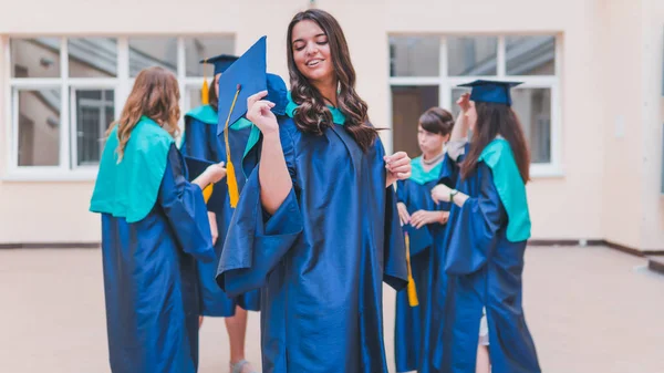 Un grupo de jóvenes graduadas. Mujer graduada es sonriente ag — Foto de Stock