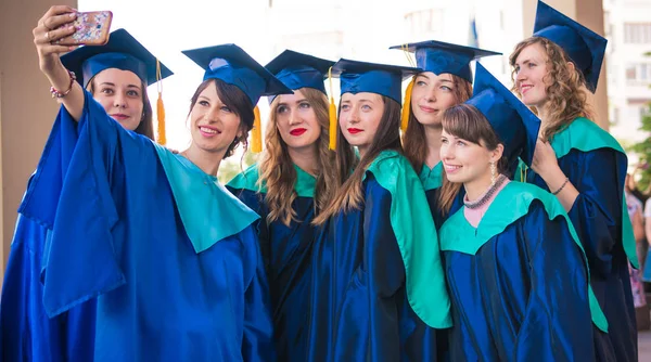 Un grupo de jóvenes graduadas. Mujer graduada es sonriente ag —  Fotos de Stock