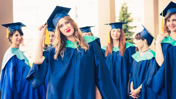 Un grupo de jóvenes graduadas. Mujer graduada es sonriente ag —  Fotos de Stock