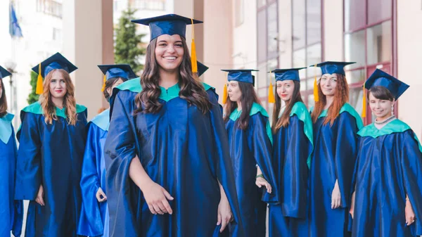 Un grupo de jóvenes graduadas. Mujer graduada es sonriente ag —  Fotos de Stock
