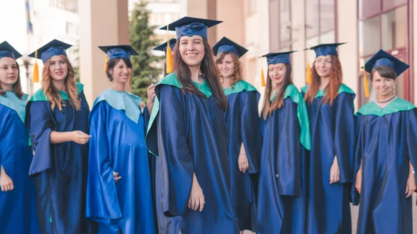 Un grupo de jóvenes graduadas. Mujer graduada es sonriente ag —  Fotos de Stock