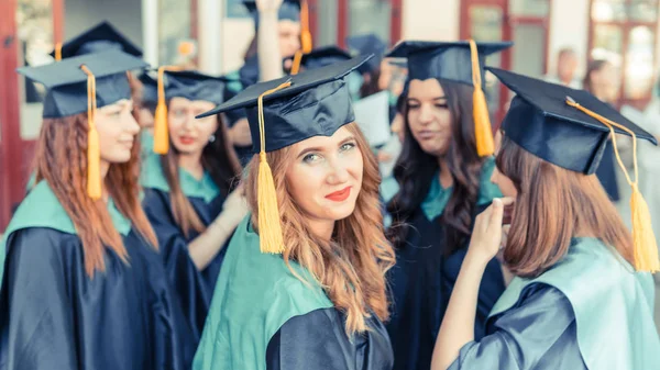 Un grupo de jóvenes graduadas. Mujer graduada es sonriente ag —  Fotos de Stock