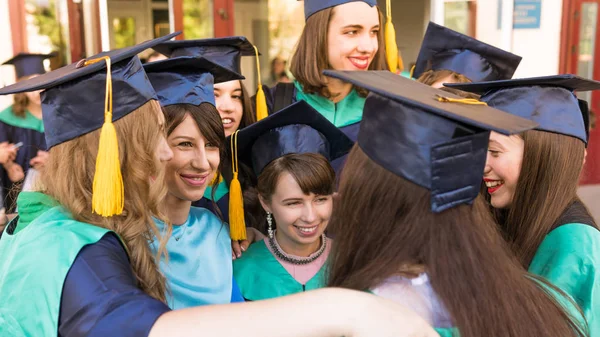 Un grupo de jóvenes graduadas. Mujer graduada es sonriente ag —  Fotos de Stock