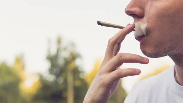 Молодой человек курит медицинскую марихуану на открытом воздухе. The y — стоковое фото