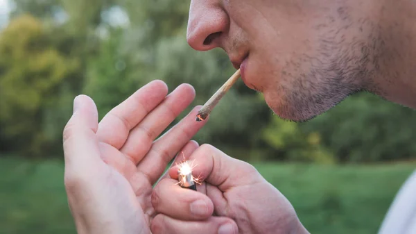 Молодой человек курит медицинскую марихуану на открытом воздухе. The y — стоковое фото